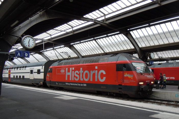 La Fundaci�n que gestiona los trenes hist�ricos de los Ferrocarriles federales suizos, pasea este enorme logo en los laterales de la 460-102 en la estaci�n de Z�rich con un tren regional de dos pisos.