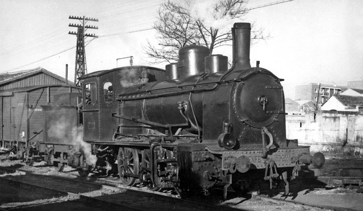 Perspectiva de la locomotora de vapor 030-2531 en Salamanca con un vag�n cerrado de mercanc�as, de madera. Tras ella se ven edificios de viviendas. Archivo Hist�rico Ferroviario FE-0009-015