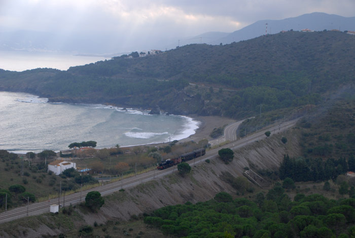 Autor: MARC LLINAS.  El tren circulando junto a la playa de Garvi, entre Colera y Portbou