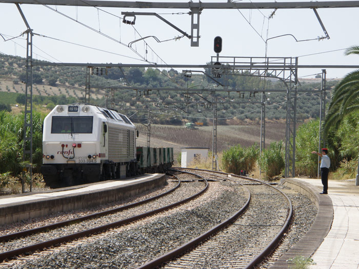 El factor, situado en el extremo del and�n, recibe al tren de tolvas, remolcado por la 333-394-5, que entra a marcha lenta, indic�ndole que se sit�e en piquetes junto al paso a nivel